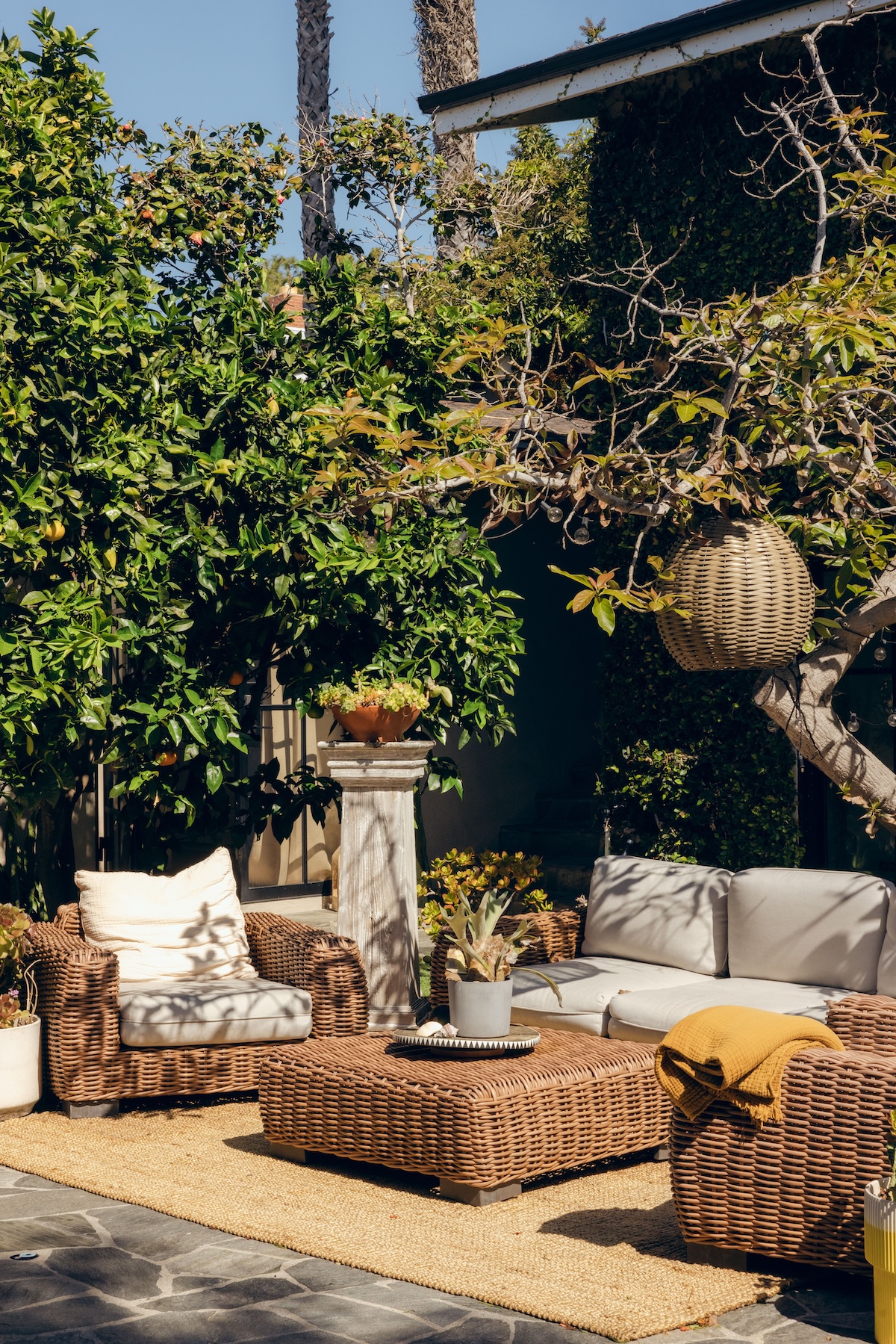 Inviting garden patio with woven seating, natural textures and a yellow throw